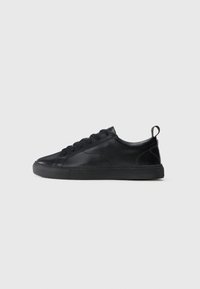 Black leather sneaker with a smooth texture, lace-up design, flat rubber sole, and a small back loop for easy wear. Subtle stitching accents.