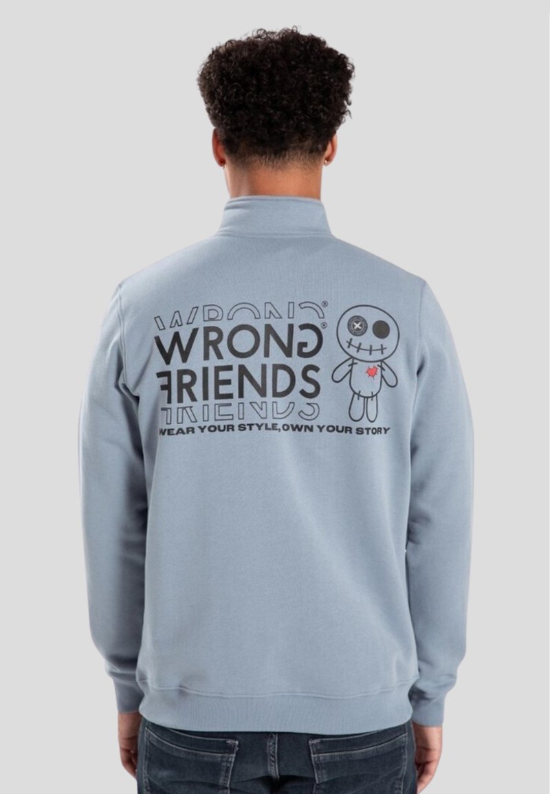 Ljust blå sweatshirt med hög krage, prydd med svart text och en karaktärsgrafik på baksidan. Mjuk textur, avslappnad passform.