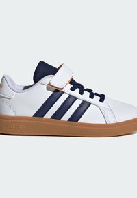 Zapatillas blancas con rayas azul marino, suela de goma, lengua de textil y correa de Velcro. Parte superior de cuero suave con detalles de costura en contraste.