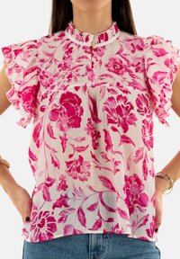 Blusa floral de tejido ligero y transparente con flores en tonos rosa y fucsia. Mangas con volantes y cuello mandarina con cierre de botón.