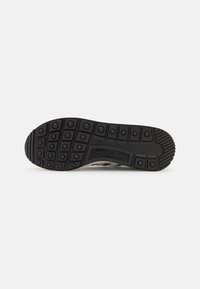 Black sneaker sole with textured grips, featuring the Adidas logo. The design includes circular indentations for traction.