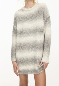 Pull en tricot gris et blanc dégradé avec manches longues, encolure ronde et poignets côtelés. Texture douce avec une coupe décontractée.