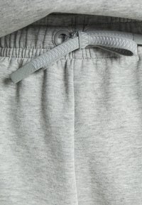 Calças de treino cinzentas em algodão com um cós elástico e cordão. Textura suave com um padrão mesclado subtil e detalhes cosidos.
