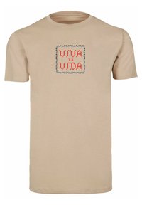 Beige bomull t-skjorte med et firkantet grafisk motiv med teksten "VIVA LA VIDA" i rødt og blått, rammet inn av et dekorativt mønster.