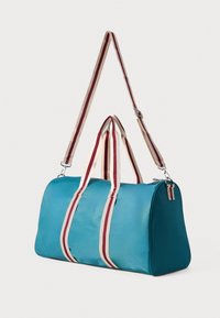Borsa a tracolla teal con manici a strisce beige e bordeaux e tracolla regolabile, appoggiata su uno sfondo bianco semplice.