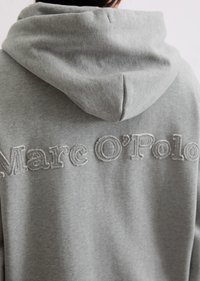 Sweatshirt gris avec une texture douce, arborant le texte brodé "Marc O'Polo" dans le dos. Comprend une capuche avec cordon de serrage et une coupe décontractée.