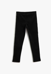 Leggings negros hechos de una tela suave y elástica. Tienen una cintura elástica y piernas ajustadas con un corte ceñido. Sin patrones ni adornos visibles.