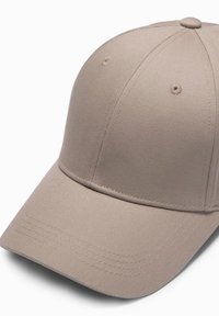 Beige baseball cap lavet af tekstureret stof. Har en buet skygge, seks ventilationshuller og subtile syninger.