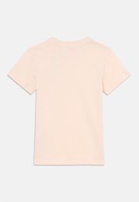 T-shirt à manches courtes de couleur pêche clair avec un col rond, fabriqué en coton doux. Texture lisse et design simple, sans graphiques ni motifs.