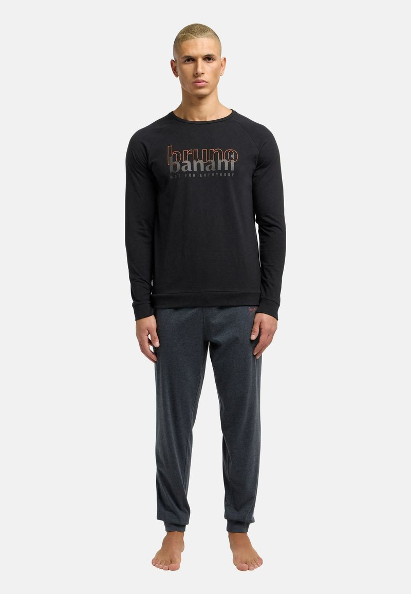 Sort langærmet top med "bruno banani" logo, der er parret med grå joggingbukser, begge lavet af blødt stof. Modellen er barfodet.