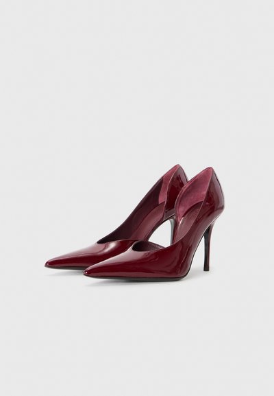 Burgundy patent leather heels, pointed toes, cut-out sides, and thin stiletto heels. Smooth texture with a glossy finish.