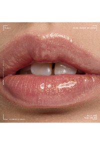 Gros plan sur des lèvres avec un brillant à lèvres rose scintillant et brillant, légèrement entrouvertes, montrant un petit écart entre les dents.