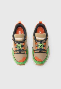 Világosbarna és zöld sportcipők narancssárga részletekkel, pixeles mintával, hálós felsőrésszel, texturált talppal, „Minecraft” logóval és karakter ikonnal.