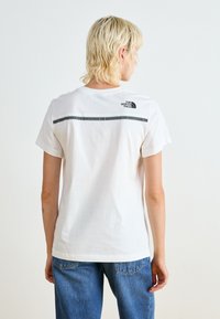 Witte katoenen T-shirt met een ronde hals, korte mouwen en een zwart logo op de bovenrug. Ontspannen pasvorm met een gladde textuur.