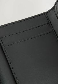 Produit en simili cuir noir comportant trois emplacements pour cartes. Texture lisse avec de fines coutures le long des bords.
