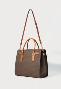 Sac fourre-tout en monogramme marron avec des poignées en cuir beige et une bandoulière réglable, mettant en valeur des accents en chaîne dorée.
