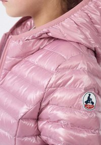 Giacca a vento rosa lucida con cappuccio, caratterizzata da sezioni verticali trapuntate e un patch rotondo sul lato sinistro della spalla.