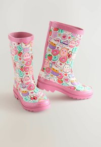 Gummistövlar har ett färgglatt mönster av godis, hjärtan och djur på en mintgrön bakgrund. Den rosa glittriga kanten ger extra detalj.