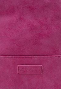 Różowa skórzana torba o gładkiej fakturze, z przeszywaną ozdobą i małą metką z logo pośrodku. Kształt prostokątny.