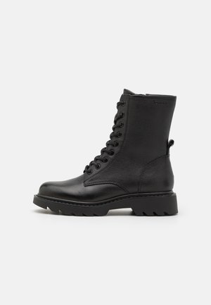 Bottes en cuir noir à lacets avec une finition texturée, bout arrondi et semelle en caoutchouc épaisse dotée d'une bande de roulement prononcée pour une meilleure traction.