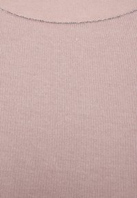 Nahaufnahme eines hell-lila gerippten Strickstoffs mit einem subtilen silbernen Fadendetail entlang der gekrümmten Ausschnittkante.