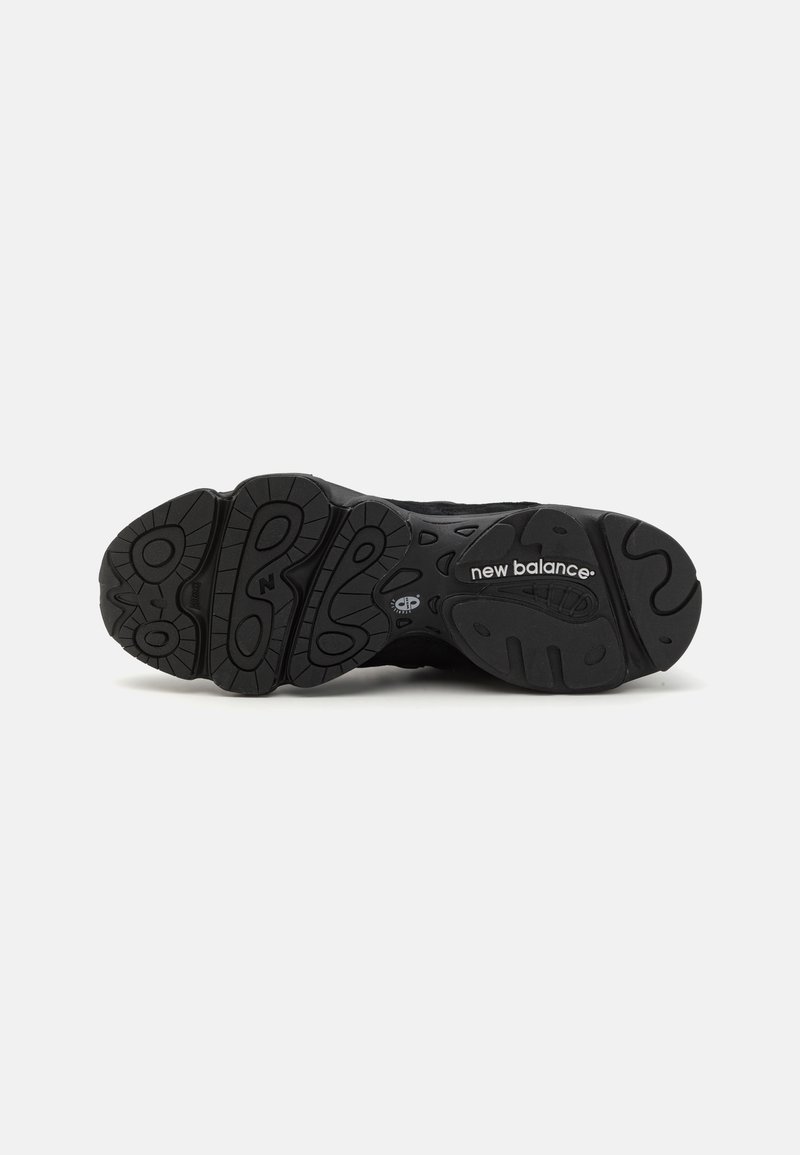 Suela de zapato deportivo negro con un diseño de goma texturizada que presenta diversas formas y patrones, incluyendo el logo de "New Balance".