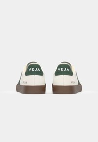 Leather sneakers with a white body, green accents on the heel, and a brown rubber sole. "VEJA" logo visible on the heel and side.