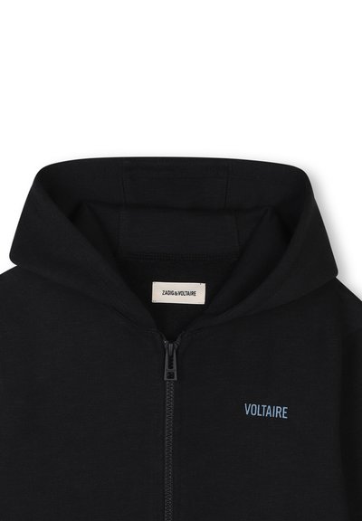 Haut de sweatshirt zippé noir avec capuche, portant un petit logo bleu "VOLTAIRE" sur la poitrine gauche, fabriqué à partir d'un tissu flexible. Design simple.