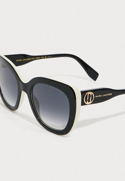 Sorte og hvide firkantede Marc Jacobs solbriller med gradient mørke linser og guldlogo-accenter på stængerne.