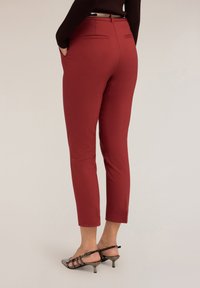 Röda skräddarsydda byxor med slim fit, som har sidofickor, en mjuk textur och midjehöjd. Bak finns två horisontella fickor med piping.