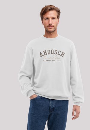 Weißes Sweatshirt mit Rundhalsausschnitt und langen Ärmeln. Verfügt über ein großes bedrucktes Textdesign in Braun. Kombiniert mit blauen Jeans.
