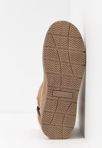 Chaussure en daim marron avec semelle en caoutchouc texturée affichant un motif en zigzag. Présente un petit logo et une étiquette indiquant la taille 37.
