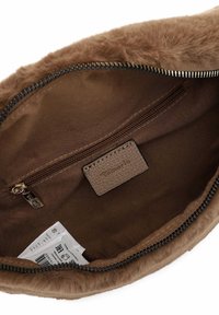 Intérieur d'un sac en fausse fourrure marron avec une poche zippée, une étiquette texturée et une doublure en tissu. La couleur est uniforme sans motifs visibles.