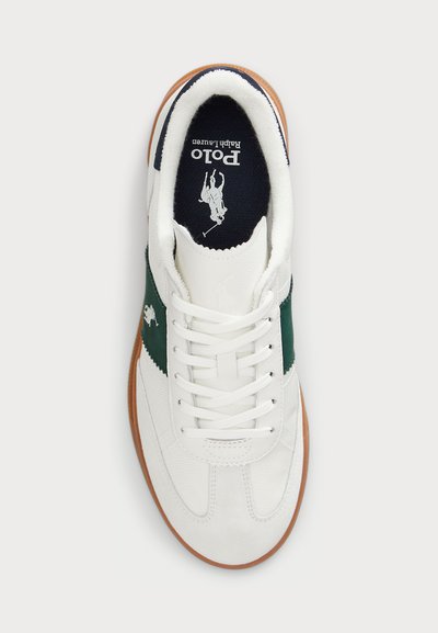 Λευκά αθλητικά παπούτσια με πράσινες και ναυτικές λεπτομέρειες, υφασμάτινη υφή και λείο δέρμα. Διαθέτουν καουτσούκ σόλα και κορδόνια για ασφαλή εφαρμογή. Ο λογότυπος Polo είναι ορατός.