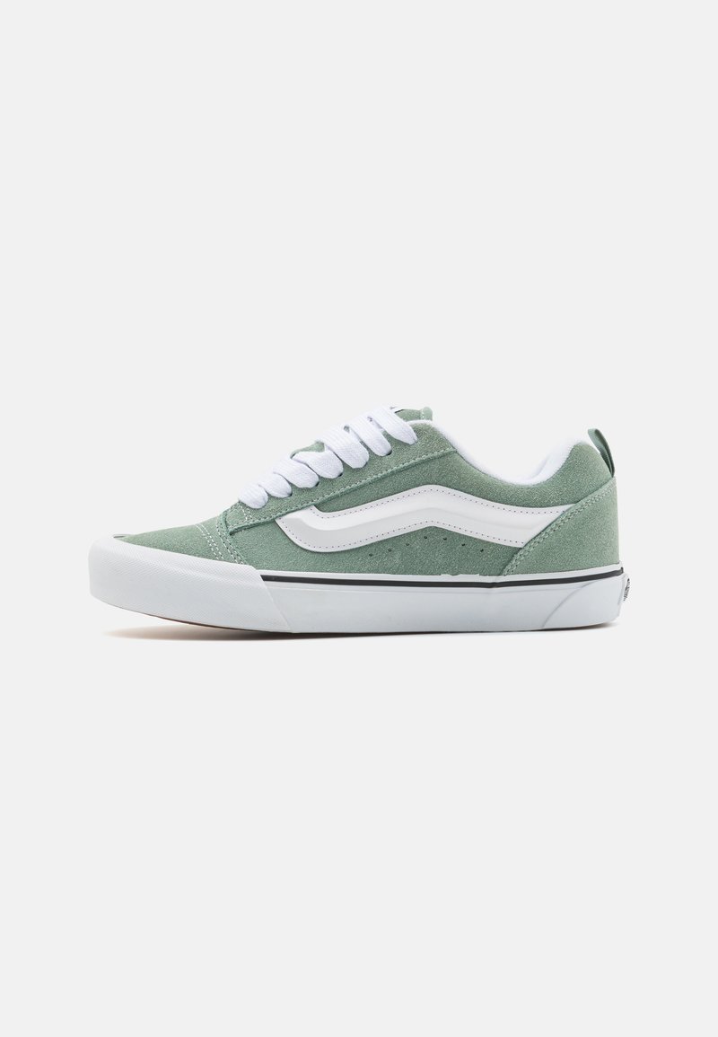 Grønn semsket sneakers med hvite lisser, med en hvit sidestripe, en svart gummisåle, og subtil tekstur for grep.