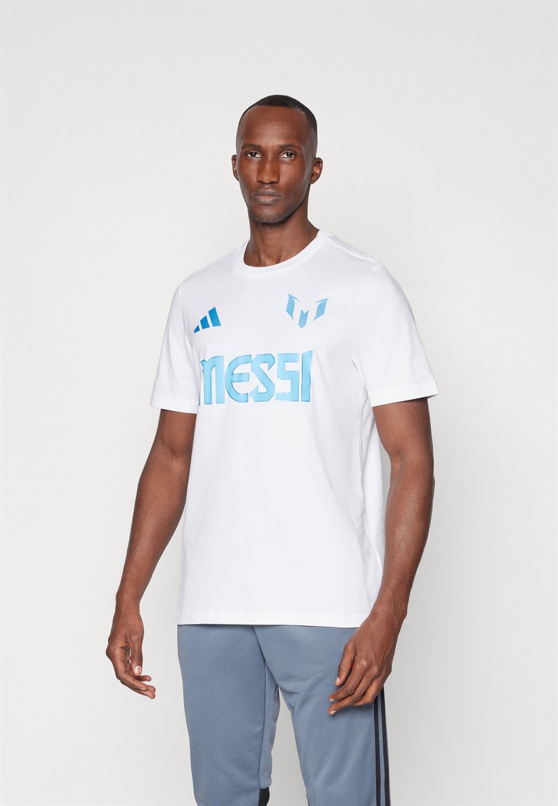 Hvid bomulds t-shirt med blå "MESSI" tekst, tre blå striber og et logo på brystet, med korte ærmer og rund halsudskæring.