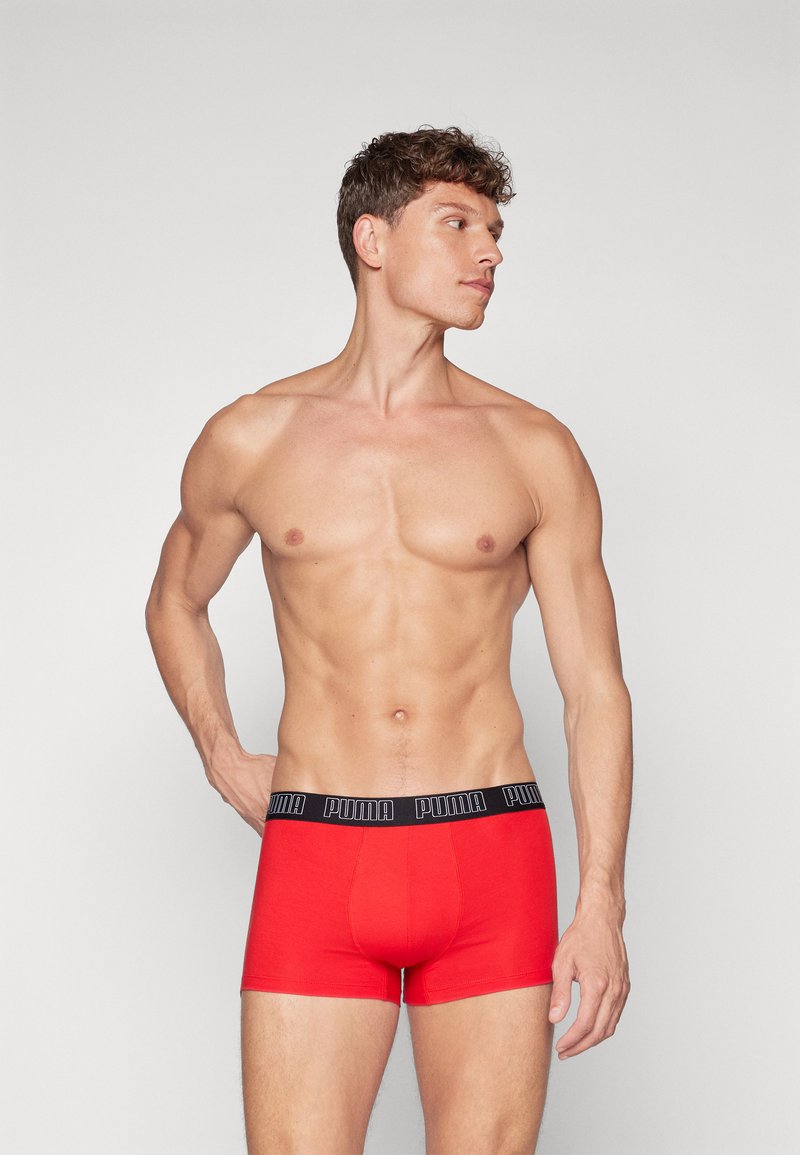 Caleçons boxers rouges avec une ceinture élastique noire arborant le logo "PUMA". Texture lisse et design ajusté, portés par un mannequin masculin.
