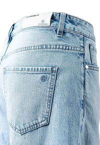 Light blue denim jeans with back pocket and white label showing brand name "ELIAS RUMELIS" on waistband.