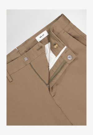 Des pantalons en coton marron avec une fermeture éclair, un bouton et une doublure intérieure blanche. L'étiquette indique "NN. 07". Texture unie sans motifs.