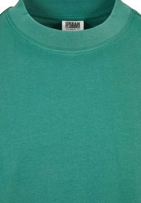 Tricou verde cu mânecă scurtă, guler rotund, fabricat din bumbac organic, având o textură fină și un design simplu, fără modele.