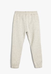 Lys grå sweatpants med en blød tekstur, elastisk talje og smalle benender. Har et subtilt meleret mønster over det hele.