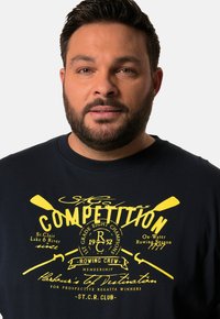 Námořnické tričko s žlutým grafickým designem, zobrazujícími veslování a text. Podrobnosti o členství v posádce a téma soutěže jsou jasně zobrazeny.