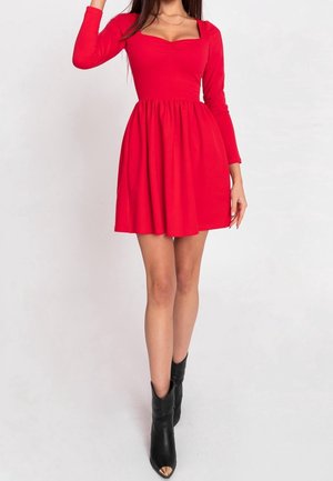 Vestido rojo de mangas largas, escote cuadrado, cintura fruncida y falda acampanada. Combinado con botas negras hasta el tobillo con punta afilada.