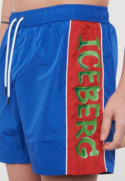Shorts de bain bleu avec un panneau latéral rouge arborant de grandes lettres vertes "ICEBERG", des rayures blanches et une taille élastique avec cordon de serrage.