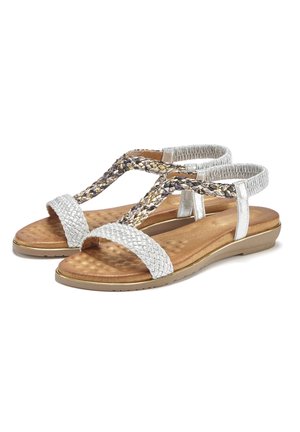 Silver braided sandals with a cushioned brown insole, flat sole, and adjustable straps. Features a textured, woven design on straps.