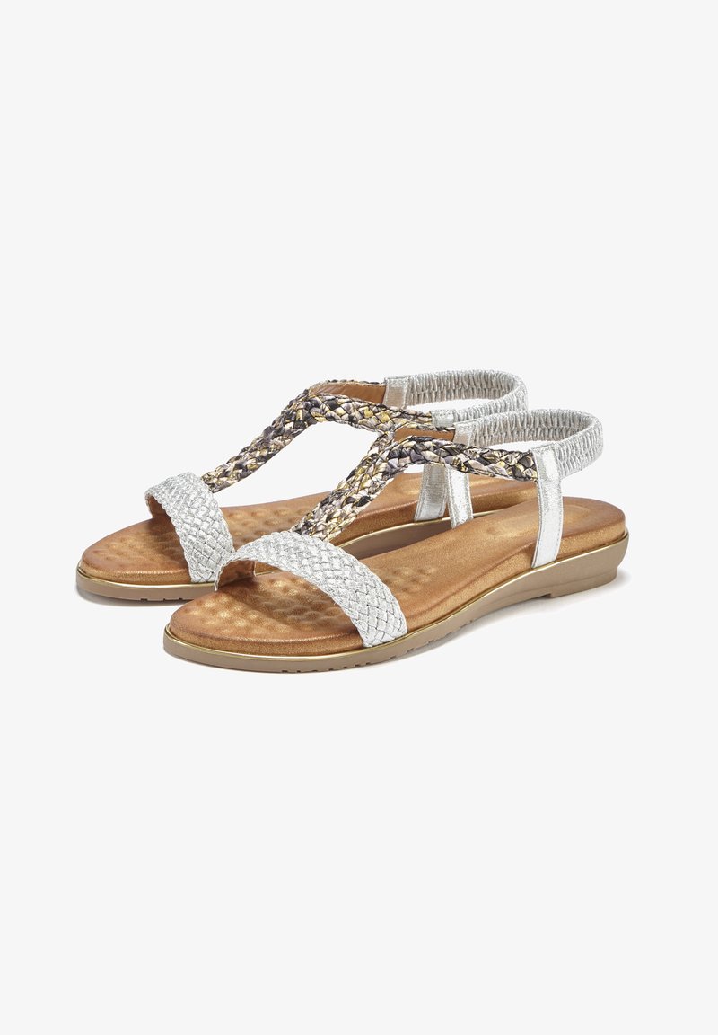 Silver braided sandals with a cushioned brown insole, flat sole, and adjustable straps. Features a textured, woven design on straps.