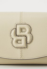 Beige teksturert lær clutch med preget logo. Har kontrasterende søm og en glatt, buet klaffelukking.