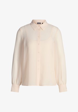 Cremefarbene Langarmbluse mit spitzem Kragen, durchgeknöpftem Vorderteil und taillierten Manschetten, gefertigt aus leichtem, transparentem Stoff.