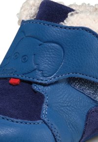 Scarpa per bambini in pelle e camoscio blu con motivo di elefante, accentata in rosso e foderata in morbido fleece nella parte superiore. Chiusura in velcro per una facile vestibilità.