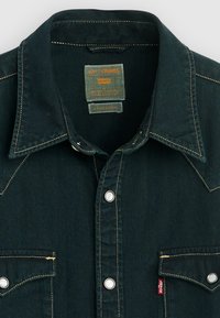 Dark denim button-up shirt with a pointed collar, white stitching, two front pockets, and a Levi's label on the side hem.